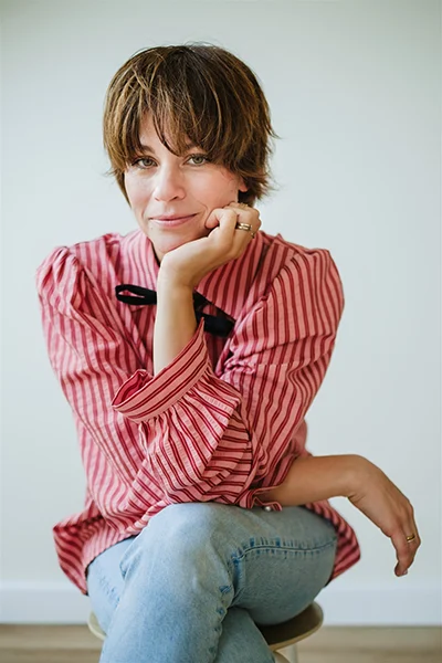 Lena Heinmann Fotografin, sie stützt das Kinn auf die Hand beim Sitzen