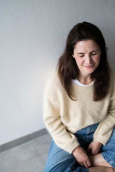 Lena-Heinemann-Portraetfotografie-FLINTA-Stuttgart-12 Lena Heinemann Porträtfotografie Stuttgart, Bild einer Frau in einem gelben Pullover leicht von oben, sie sitzt auf dem Boden und hat die Augen geschlossen