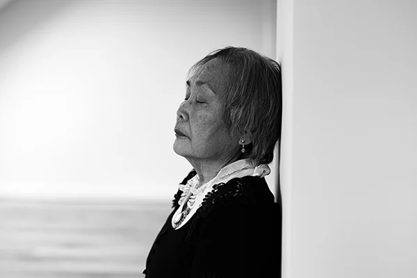 Lena Heinemann Porträtfotografie Stuttgart, Bild einer Frau, die mit geschlossenen Augen an einer weißen Wand lehnt